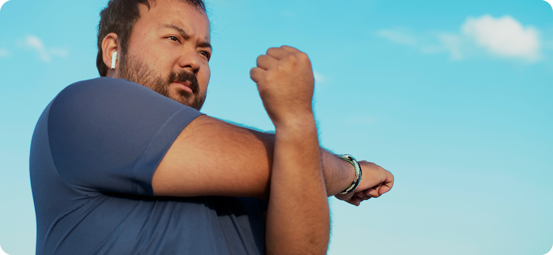 Man stretching outdoors with a clear blue sky in the background