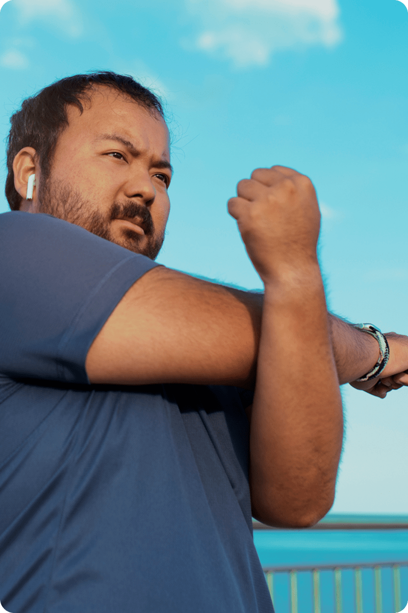 Man with a beard and earbuds against a blue sky